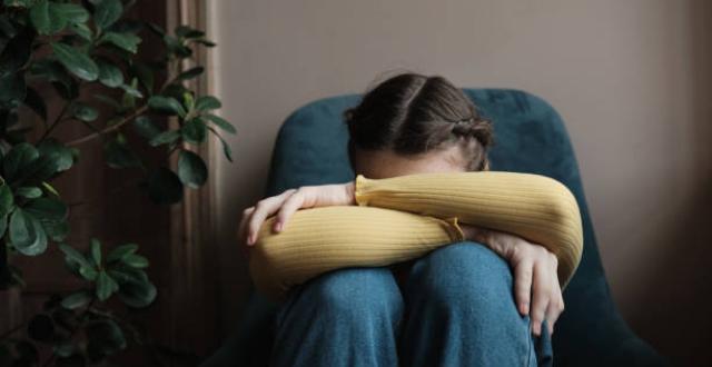 jeune fille pull jaune tête dans les genoux, triste